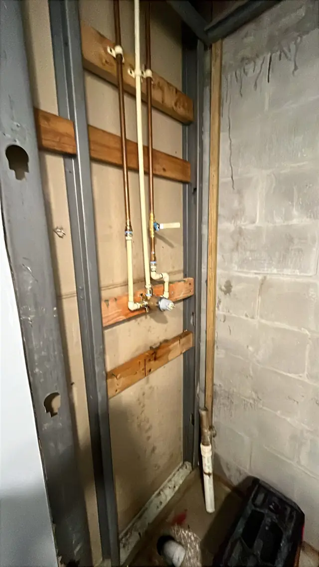 Open wall showing new copper and CPVC supply lines and a valve fixed to wood blocking